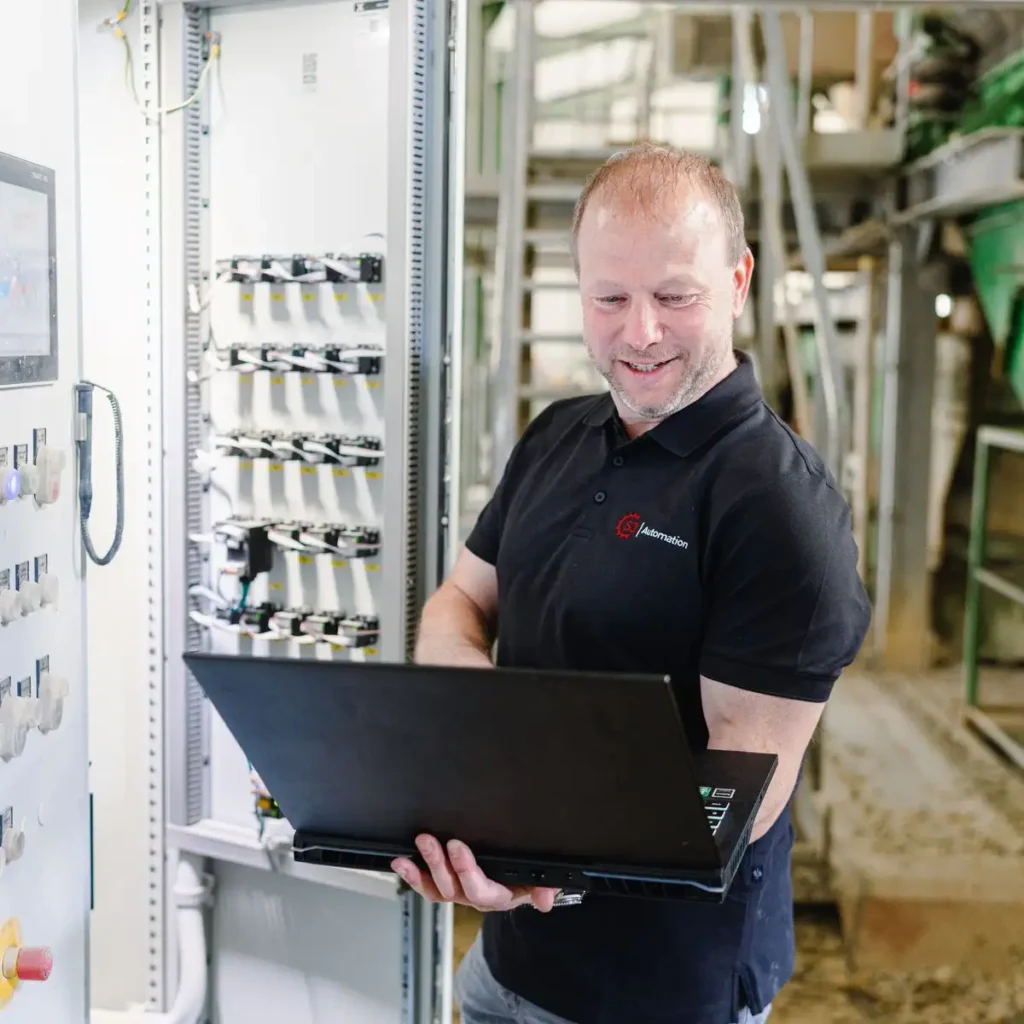 kopfmedia-sj-automation-socialmedia-116 Jürgen Sunderer mit Laptop bei der Inbetriebnahme und Software-Optimierung an einem industriellen Schaltschrank vor Ort im Werk.